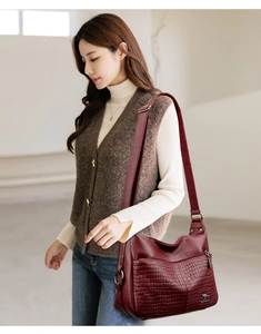 Detail of burgundy soft leather shoulder bag featuring crocodile texture and metallic logo