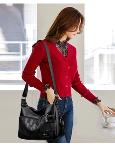 Detailed view of black woven faux leather handbag with adjustable wide shoulder strap