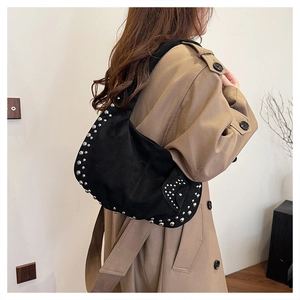 Detail of black suede hobo bag featuring silver stud trim and heart patchwork design