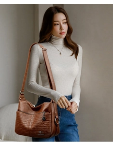 Close-up of caramel crocodile-embossed leather handbag with adjustable shoulder strap
