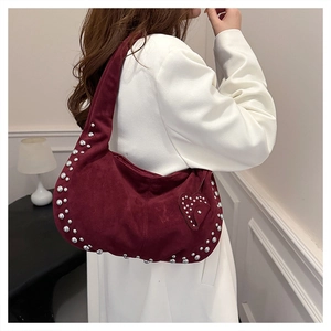 Macro detail of burgundy suede crescent bag featuring silver studs and heart charm