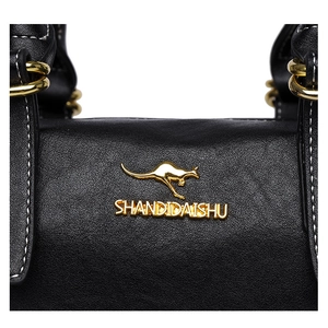 Detail of black pebbled leather texture with gold kangaroo logo and metal ring hardware