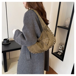 Detail view of military green suede hobo bag with silver studs and heart-shaped applique