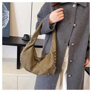Detail of olive green suede hobo bag with silver studs on a grey wool coat model