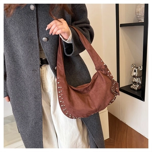 Detailed macro view of the brown suede hobo bag with silver metallic rivets and wide strap