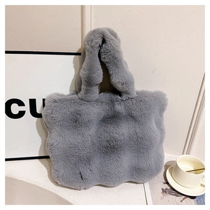 Detailed view of the soft faux fur texture and wavy edge of the gray plush bucket bag
