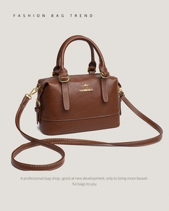 Detail of a brown lychee-patterned Boston bag with gold kangaroo logo and sturdy dual handles