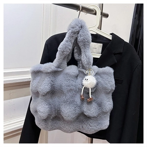 Detail of grey plush faux fur bucket bag with wavy texture and white pompom charm