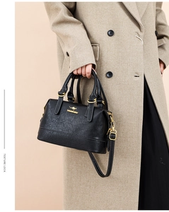 Close-up of black leather Boston bag with gold kangaroo logo and sturdy top handles