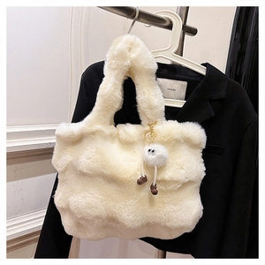 Detailed view of cream plush bucket bag with a cute monster pendant on a black blazer