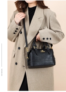 Detail view of black leather Boston bag featuring gold kangaroo logo and polished hardware