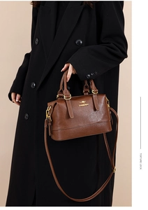Detail of premium brown leather Boston bag with gold kangaroo logo and sturdy dual handles