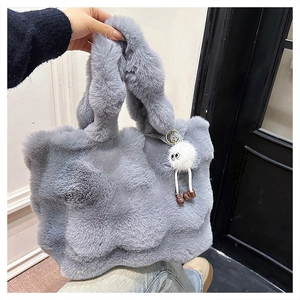 Detail of grey faux fur bucket bag with a cute white monster plush keychain charm