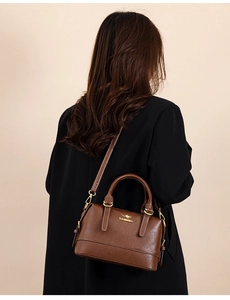 Detail of brown leather Boston bag with contrast stitching and golden metallic hardware