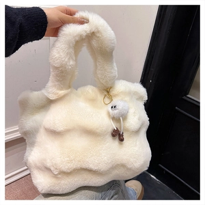 Close-up of white faux fur tote bag featuring a cute plush monster charm detail