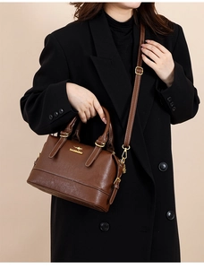 Detail of dark brown Boston bag with golden kangaroo logo and adjustable shoulder strap