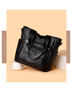 Close-up of black litchi grain faux leather tote bag with zip pockets and heart charm
