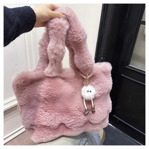 Close-up of soft pink plush bucket bag with cute white fuzzy charm and thick texture