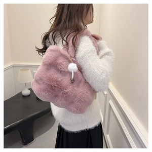 Detailed view of pink faux fur bucket bag with plush texture and white pom-pom charm