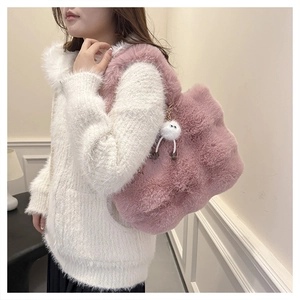 Detail of pink plush bucket bag with soft faux fur texture and cute white pompom charm