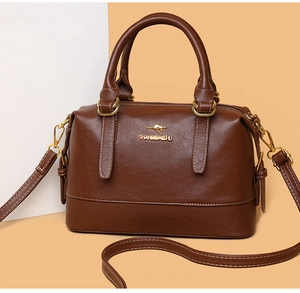Detailed view of the brown leather Boston bag with golden hardware and adjustable strap