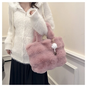 Detailed view of pink plush bucket bag with soft faux fur texture and white pompom charm