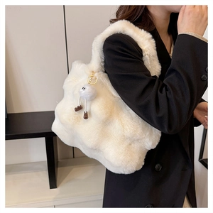 Close-up of white plush bucket bag with cute furry charm on a black blazer outfit