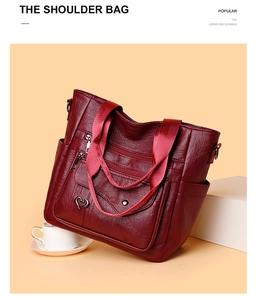 Detail of burgundy PU leather tote bag with wide strap and heart-shaped metal charm