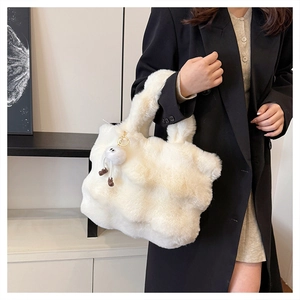 Detail of white plush bucket bag with cute furry doll charm against a black blazer