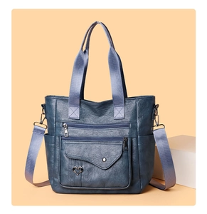 Detail of vintage blue PU leather tote bag with multi-pocket zippers and heart metal decor