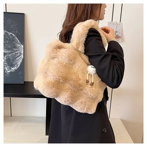 Detail of soft khaki plush bucket bag featuring a cute fuzzy white monster charm