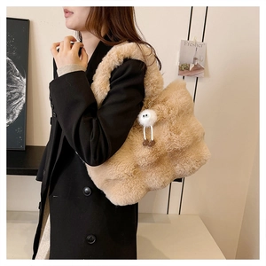 Close-up of a plush faux fur bucket bag in warm camel with a cute fuzzy eye charm