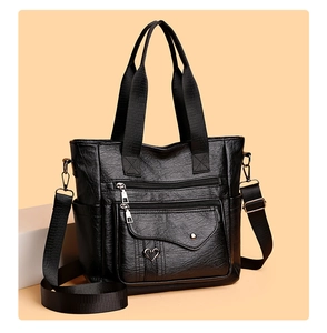 Detail view of black PU leather tote bag featuring multiple zippers and heart charm