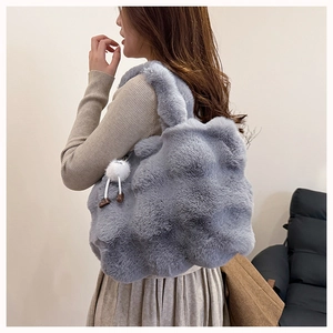 Detail of gray plush bucket bag with textured cloud pattern and white doll charm pendant