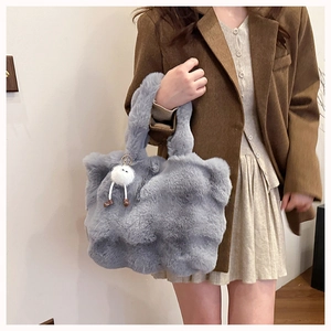 Detail of grey plush tote bag featuring soft faux fur texture and a cute pom-pom charm