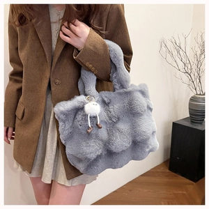 Detail of light blue faux fur bucket bag featuring a soft texture and cute pom-pom charm