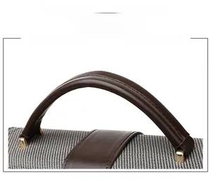 Detail of coffee brown ergonomic leather handle with precise stitching on a gray woven bag
