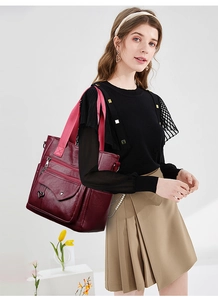 Close-up of wine red leather tote bag with functional pockets and pink fabric strap