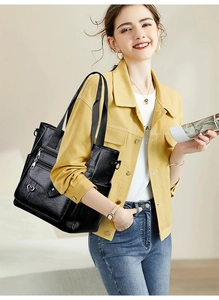 Detail of black pebbled leather tote featuring multiple zipper compartments and a heart charm