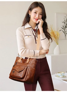 Close-up of vintage brown leather tote bag with heart charm and wide textile strap