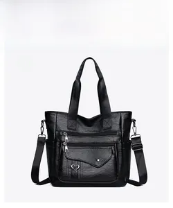 Detail of black PU tote bag featuring front zipper pockets and heart metal decoration