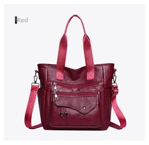 Detail view of burgundy leather tote bag with heart metal charm and zipper pockets