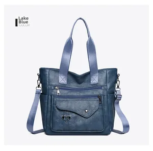 Detailed view of lake blue leather tote bag with dual zippers and woven shoulder strap