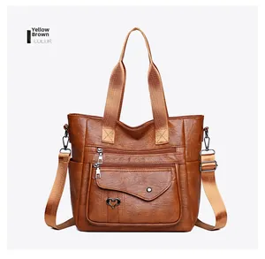 Detail of yellow-brown soft PU leather tote bag featuring heart charm and zip pockets