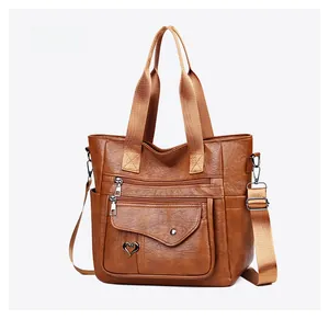 Detail of brown PU leather tote with multiple zipper pockets and heart metal decor