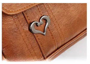 Detail of soft brown leather tote with pebble texture and metal heart ornament