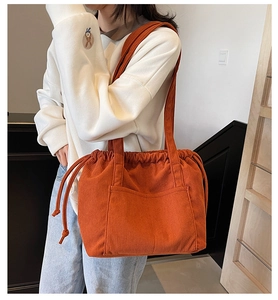Detailed view of orange corduroy tote bag with drawstring closure and front pocket