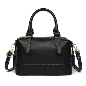 Classic black Boston bag with gold hardware and white contrast stitching on white background