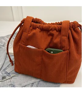 Detail of caramel corduroy tote bag featuring drawstring closure and front pocket for phone