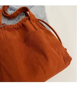 Detail of burnt orange corduroy tote bag showing ribbed texture and side pocket